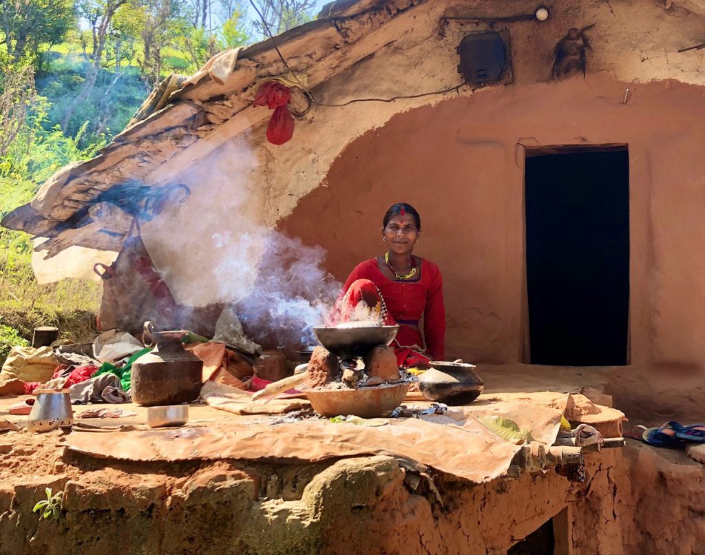 Haliya woman in front of her mud house, cooking
